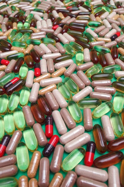 Multicolored pills and capsules on a green background