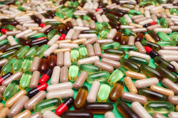 Multicolored pills and capsules on a green background