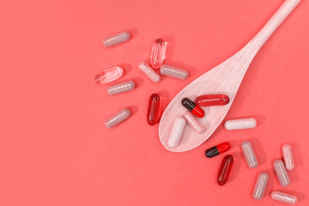 Multicolored pills and capsules on a pink background