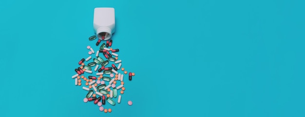 Фото Разноцветные таблетки выпадают из банки на панорамном синем фоне