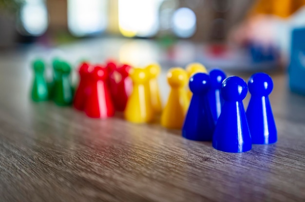 Multicolored plastic chips from a childrens board game stand on a wooden table