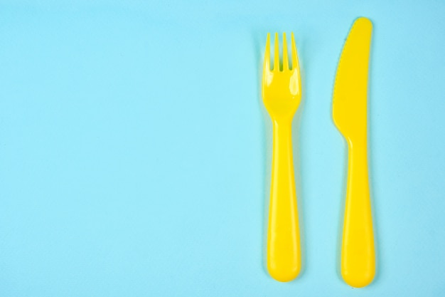 Photo multicolored plastic dishes on a blue space. the concept of environmental pollution by plastic, ecolog place for text, flat lay