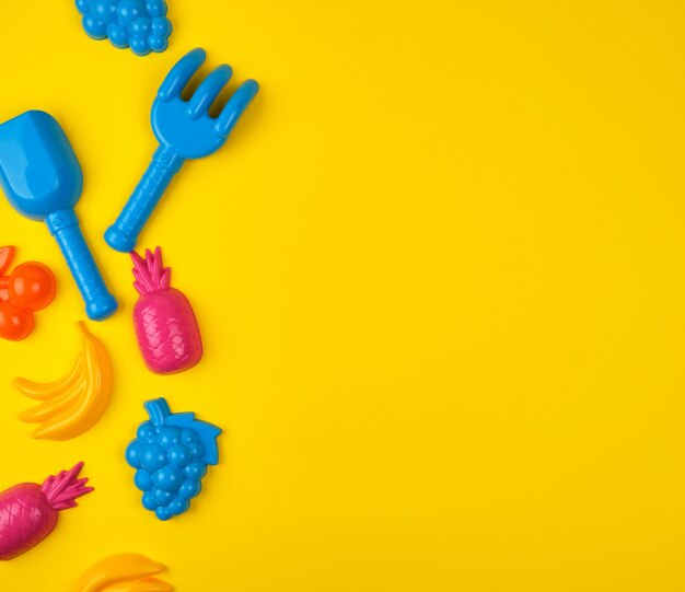 Multicolored plastic toys fruits on yellow  