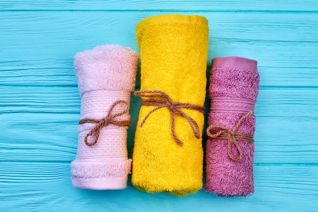 Multicolored rolled terry towels on blue desk on wood. Top view flat lay.