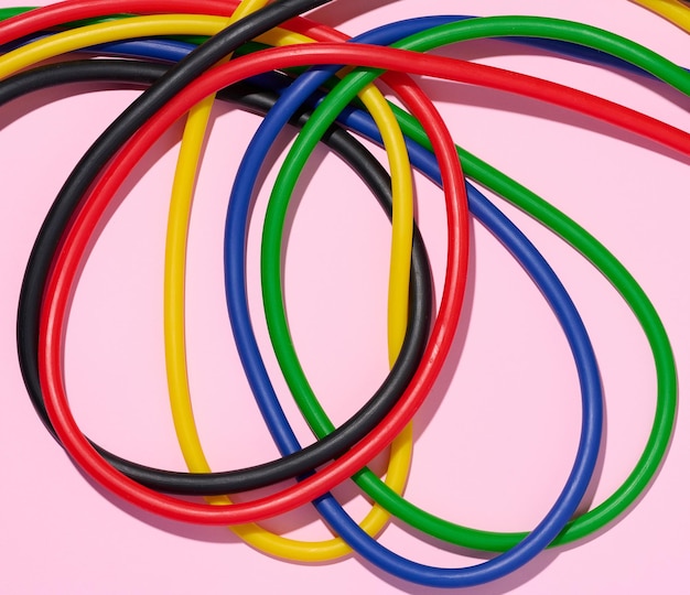 Multicolored rubber tubes on a pink background top view