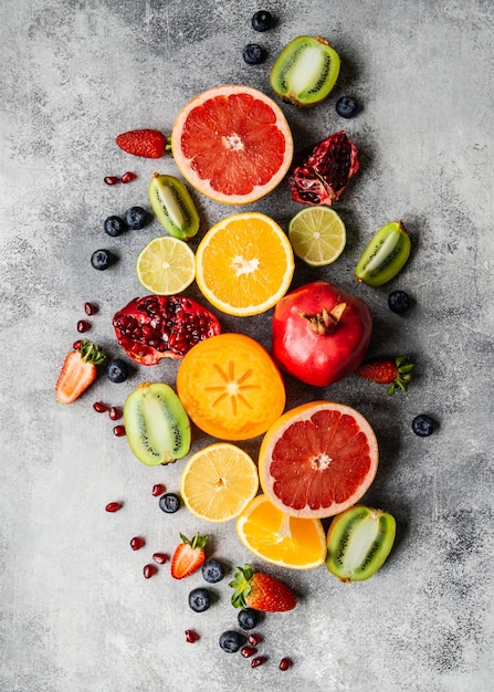 Multicolored seasonal healthy natural fruit composition with persimmon, blueberries, orange, kiwi, strawberries, grapefruit, pomegranate, orange slices.