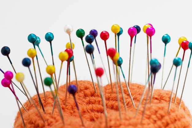 Multicolored sewing pins in the orange pin cushion 