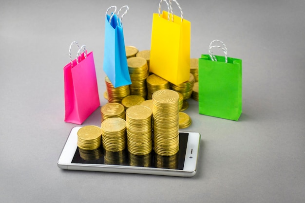 Multicolored shopbags bundle of dollars and coins on a gray background Shopping concept