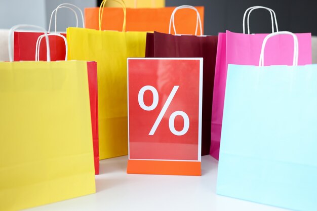 Multicolored shopping bags with percent sign. Discounts and sales concept