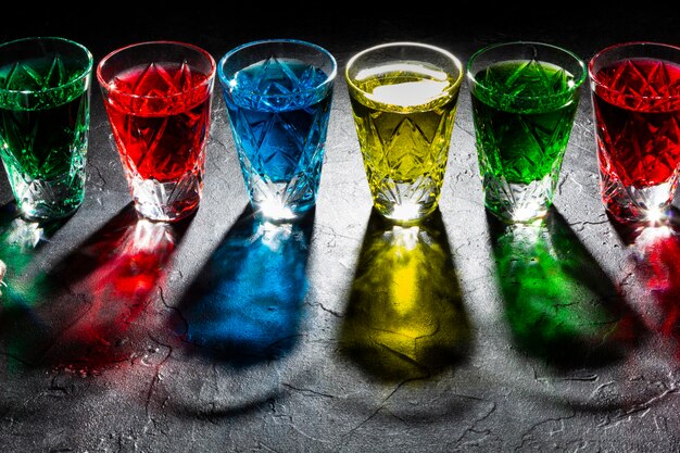 Photo multicolored shot glasses with strong alcohol. hard shadows