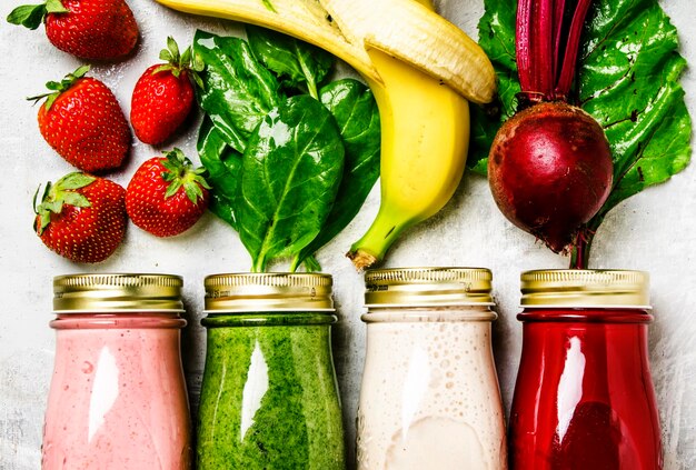 野菜、果物、ベリー、食品の背景の上面図からの色とりどりのスムージーとジュース