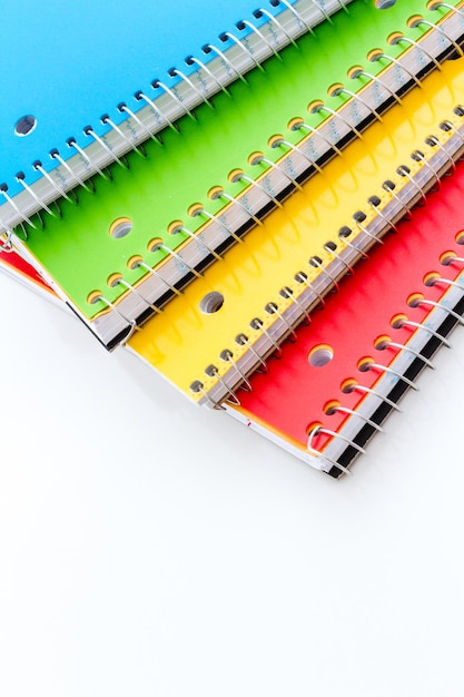 Multicolored spiral notebooks on a white background.