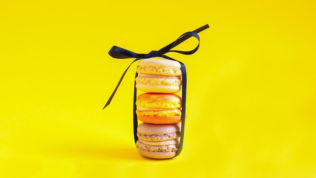 Photo multicolored stack of macarons on yellow background