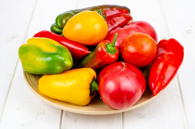 Multicolored sweet peppers and tomatoes on wooden table. Studio Photo.