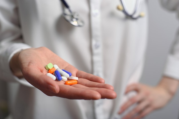 Multicolored tablets from the palm of a doctor woman with a stethoscope on the neck