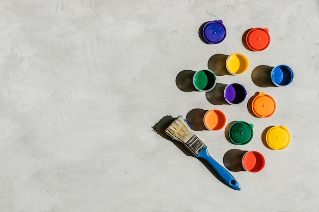 Multicolored tempera bottles and brush on concrete