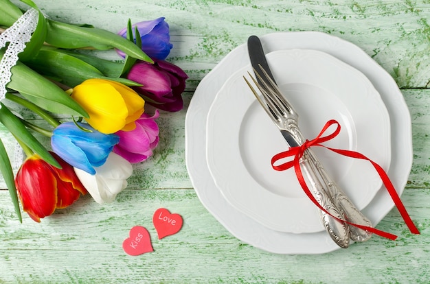 Multicolored tulips on a shabby green table. Rainbow of flowers. Menu