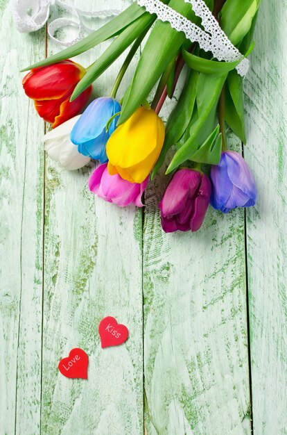 Multicolored tulips on a shabby green table. Rainbow of flowers