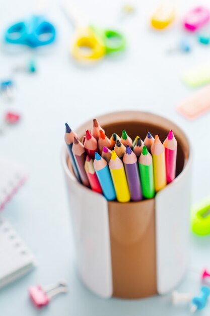 明るい青の紙の背景に学校のための色とりどりの木製鉛筆、黄色の背景に学校やオフィスの文房具。