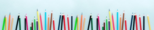 Multicolored wooden pencils for school on yellow paper surface