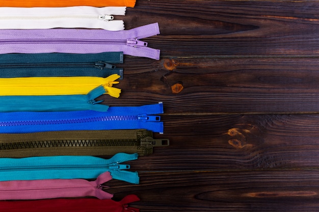 Multicolored zippers are laid out on a wooden table