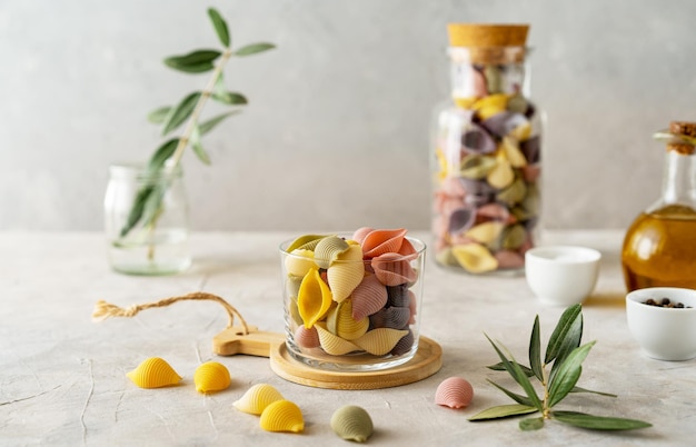 Multicoloured Italian pasta conchiglie or seashells over concrete background