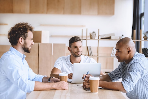 Multicultural business people working on laptop at meeting in office