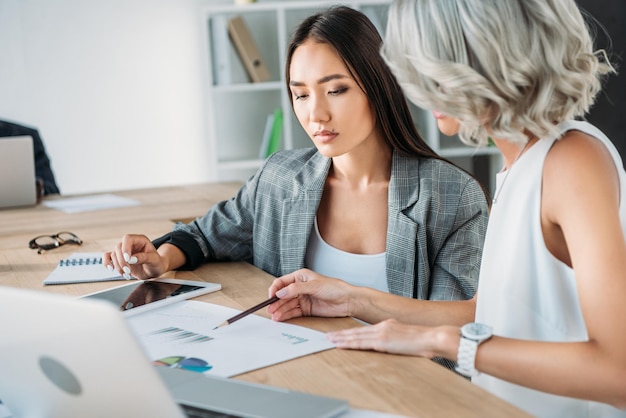 multicultural businesswomen looking at documents in office