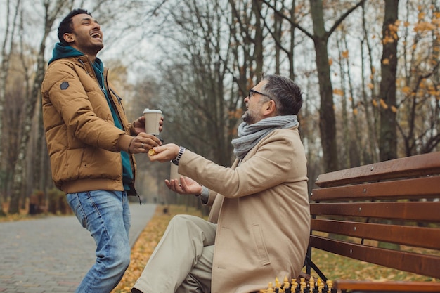 Multicultural friendship of people of different ages A meeting of two friends for a game of chess in the park