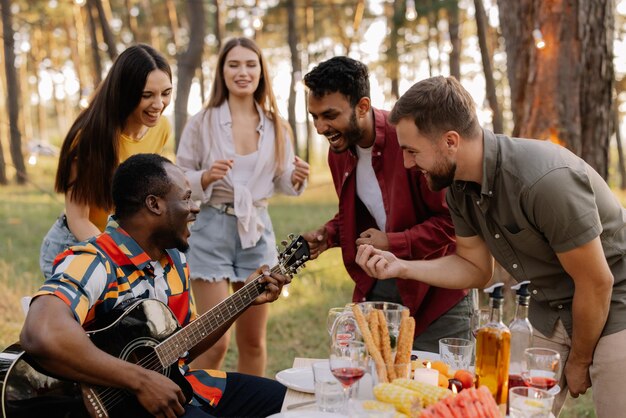 Multicultural group of people African hipster man playing guitar and friends dancing singing