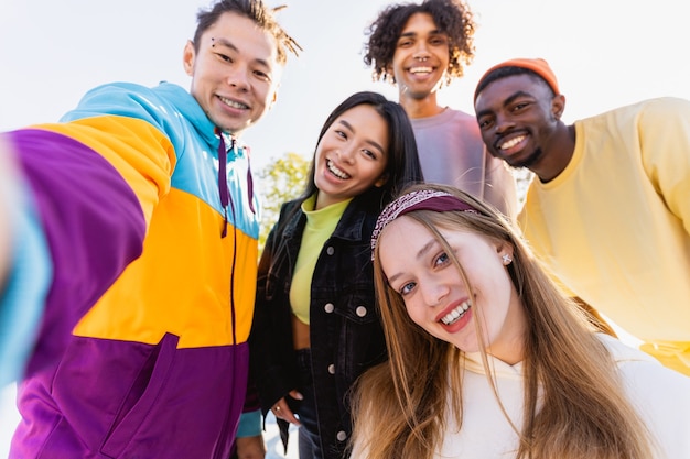 Multicultural group of young friends bonding outdoors and having fun - Stylish cool teens gathering at urban skate park