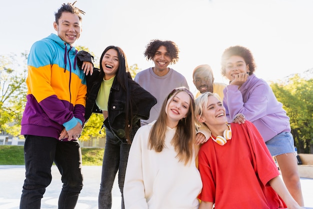 屋外で絆を深めて楽しんでいる若い友人の多文化グループ-都会のスケートパークに集まるスタイリッシュでクールな10代の若者たち