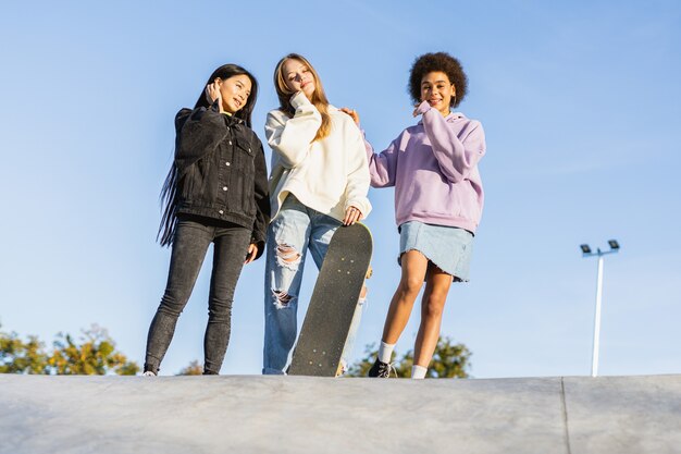 Multicultural group of young friends bonding outdoors and having fun - Stylish cool teens gathering at urban skate park