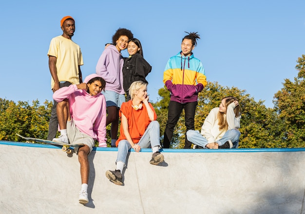 Photo multicultural group of young friends bonding outdoors and having fun - stylish cool teens gathering at urban skate park