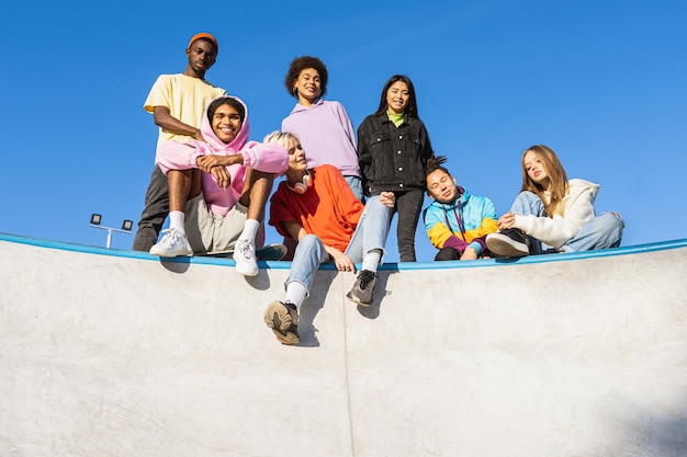 Foto gruppo multiculturale di giovani amici che si uniscono all'aperto e si divertono - ragazzi alla moda e alla moda che si riuniscono allo skate park urbano