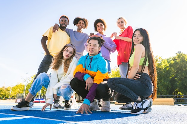 屋外で絆を深めて楽しんでいる若い友人の多文化グループ-都会のスケートパークに集まるスタイリッシュなクールな10代の若者たち