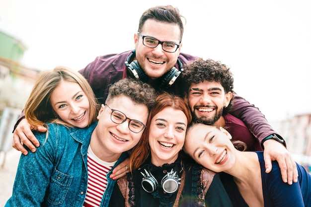 Multicultural guys and girls taking selfie outdoors with day backlight