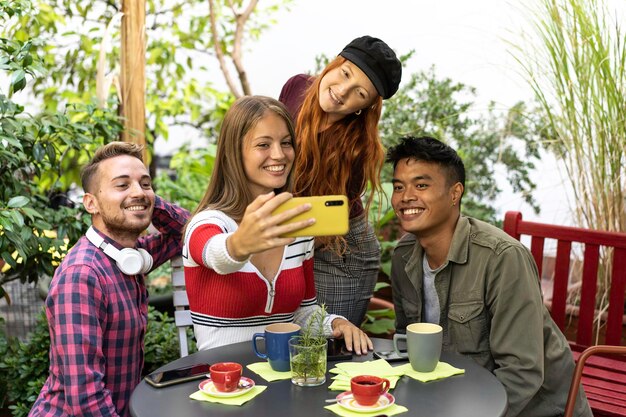 Amici felici multiculturali che si divertono a fare selfie di gruppo fuori in giardino durante una pausa caffè giovani di razza mista che ridono insieme godendosi una giornata in vacanza