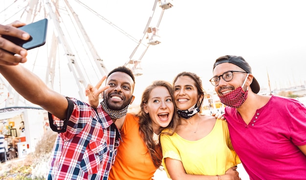 Multicultural happy travelers taking selfie wearing open face masks