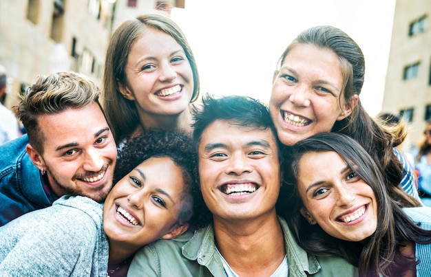 Uomini e donne multiculturali che si fanno selfie fuori con la retroilluminazione