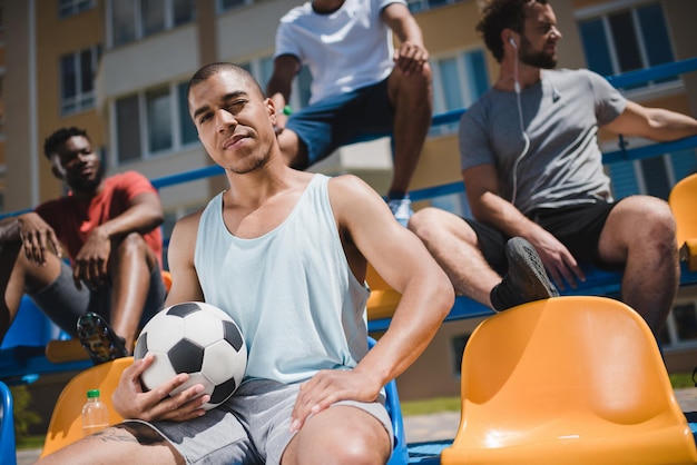 Photo multicultural soccer team resting on stadium after soccer match