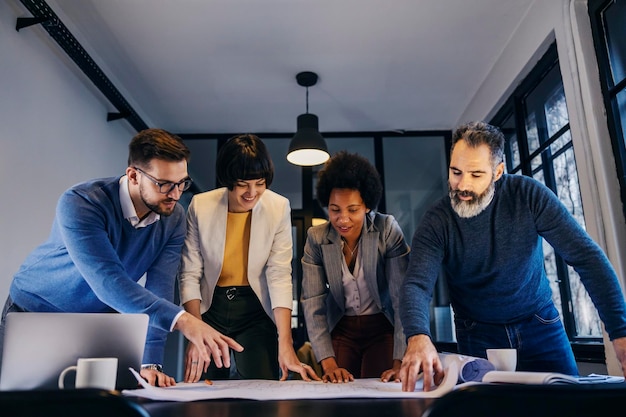 A multicultural team is standing at the office and working on architectural project