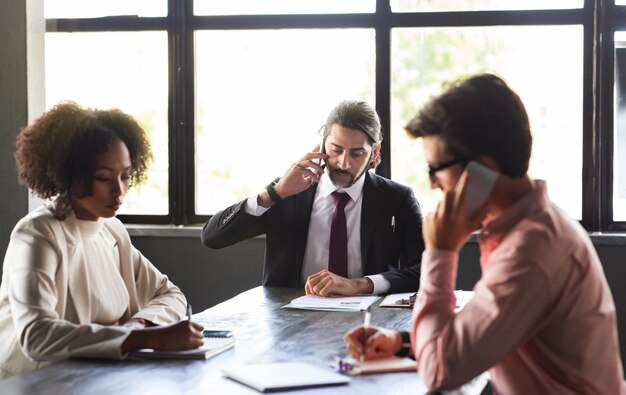 Multicultural team sitting at meeting room against window at office