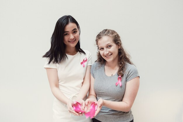 Multicultural young women with pink ribbons, breast cancer awareness