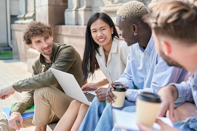 Multicultureel studententeam staat te kletsen op de trappen van de campus