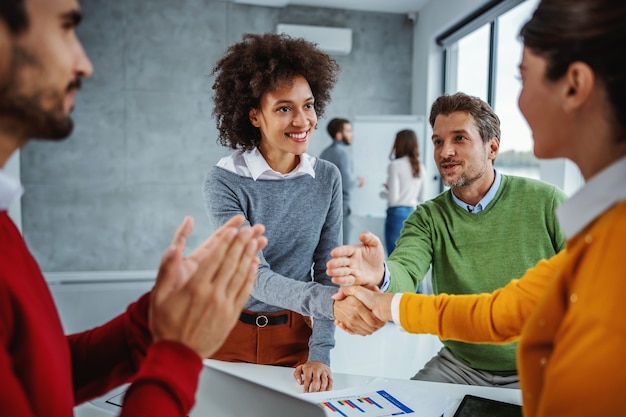 Multiculturele groep bedrijfsmensen die zich in directiekamer bevinden en vergadering hebben. twee vrouwen hadden de kans om het project op tijd af te ronden.