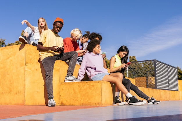 Foto multiculturele groep jonge vrienden die buiten een band hebben en plezier hebben - stijlvolle coole tieners die samenkomen in het stedelijke skatepark