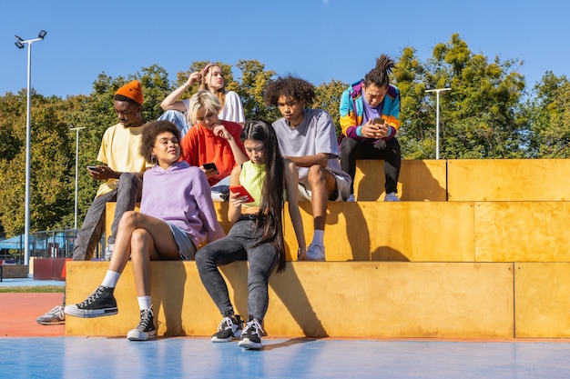 Multiculturele groep jonge vrienden die buiten een band hebben en plezier hebben - Stijlvolle coole tieners die samenkomen in het stedelijke skatepark