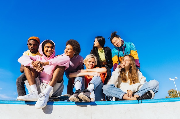 Multiculturele groep jonge vrienden die buiten een band hebben en plezier hebben - Stijlvolle coole tieners die samenkomen in het stedelijke skatepark