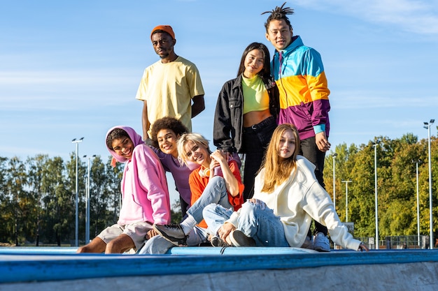 Multiculturele groep jonge vrienden die buiten een band hebben en plezier hebben - Stijlvolle coole tieners die samenkomen in het stedelijke skatepark